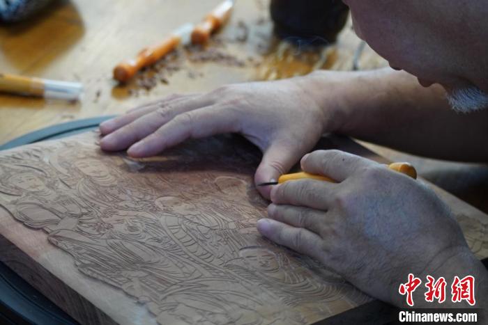圖為徐晉林湊近木板，近距離制作雕版畫(huà)?！【琶赖┰?　攝