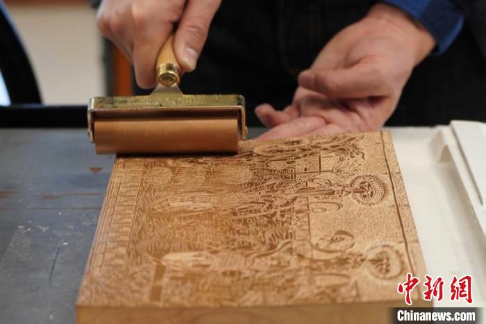 圖為徐晉林工作室工作人員正在給雕好壁畫(huà)的版面滾油墨?！【琶赖┰?　攝