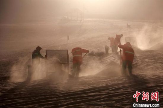 圖為敦煌市鳴沙山月牙泉景區(qū)“駱駝保姆”清理駱駝糞便?！垥粤?攝