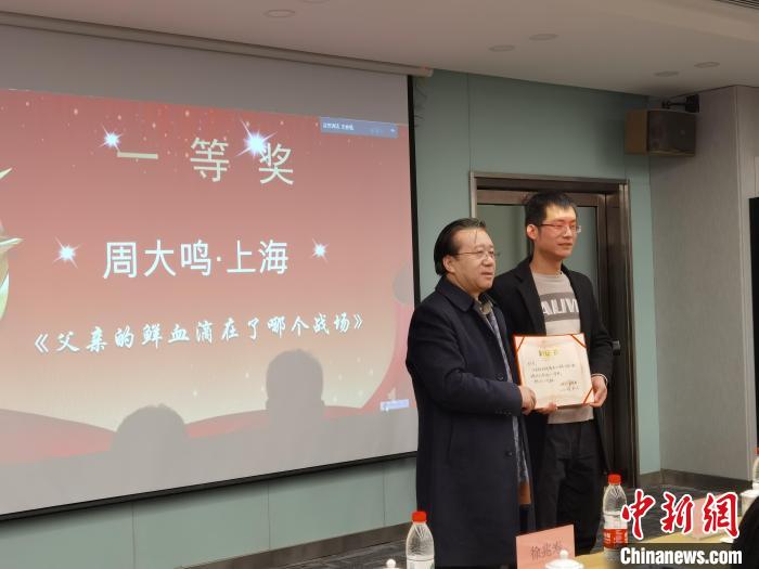 圖為作家、西北師范大學(xué)新聞與傳媒學(xué)院院長(zhǎng)徐兆壽頒發(fā)一等獎(jiǎng)證書(shū)，代領(lǐng)獎(jiǎng)?wù)呱吓_(tái)領(lǐng)獎(jiǎng)?！钅?攝