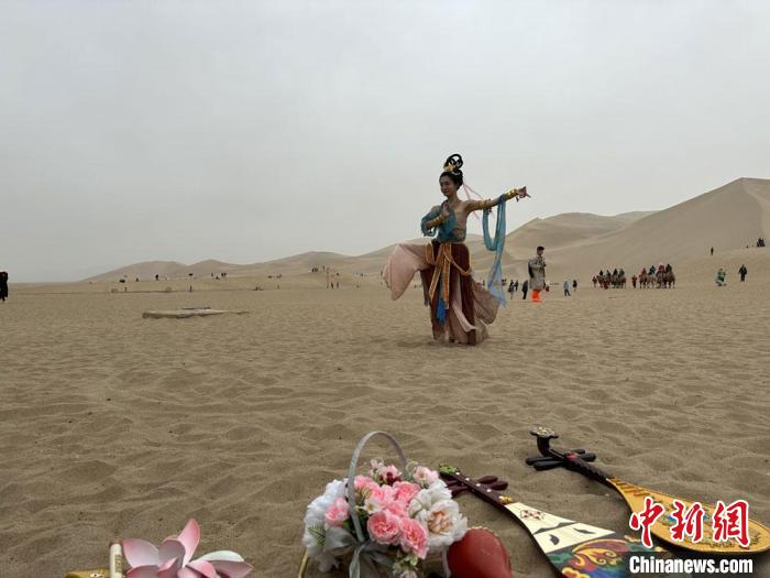 圖為2023年4月底，敦煌大漠“逐舞者”奧楠在鳴沙山月牙泉景區(qū)視頻直播敦煌舞。　馮志軍 攝