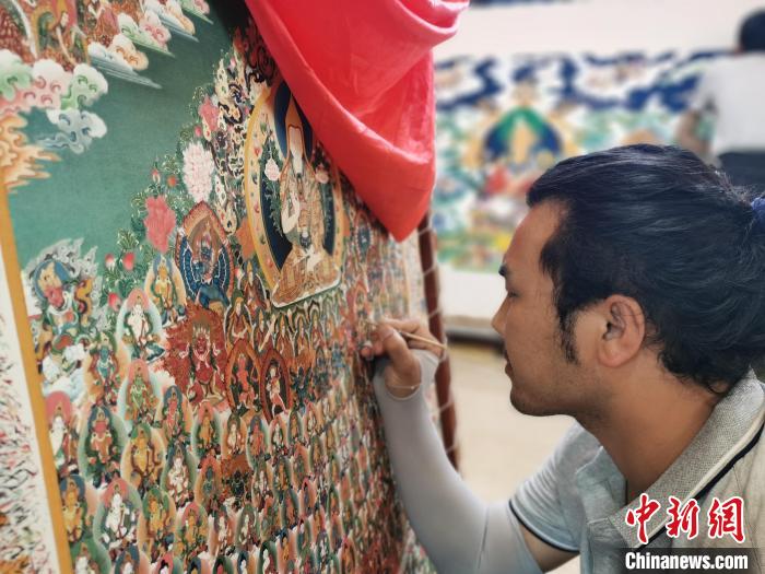 圖為更登才讓的徒弟繪畫(huà)唐卡?！?zhí)砀?攝