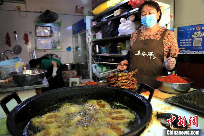 圖為平安驛·河湟民俗文化體驗(yàn)地內(nèi)的商戶炸干板魚?！⊙Φ?攝